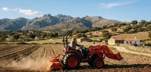 minitractor compacto trabajando en campo con monta&ntilde;as al fondo, paisaje rural de Extremadura